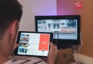man browsing tablet sitting in front of TV