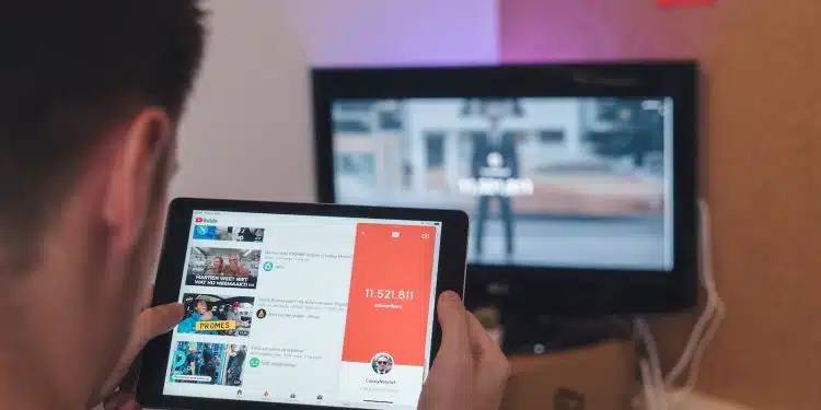 man browsing tablet sitting in front of TV